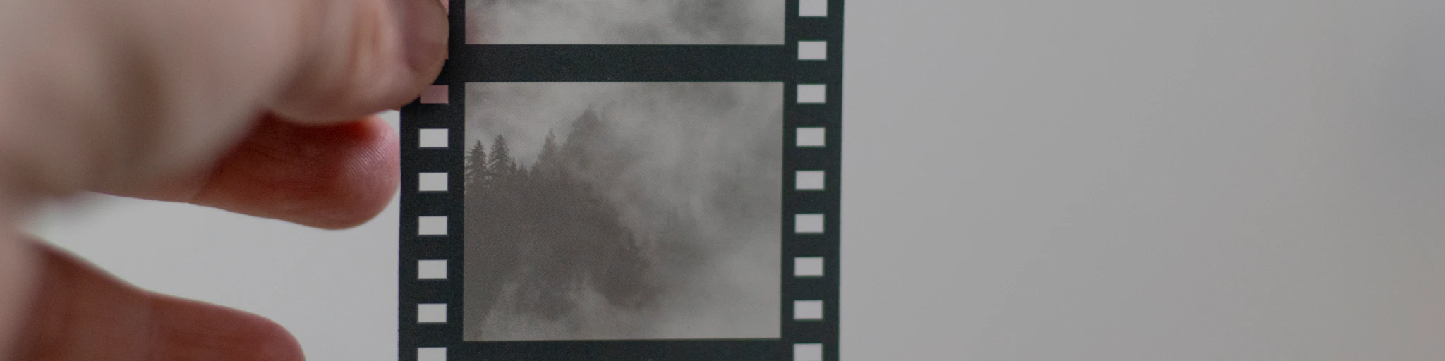 a hand holding a film strip with a mountain in the background