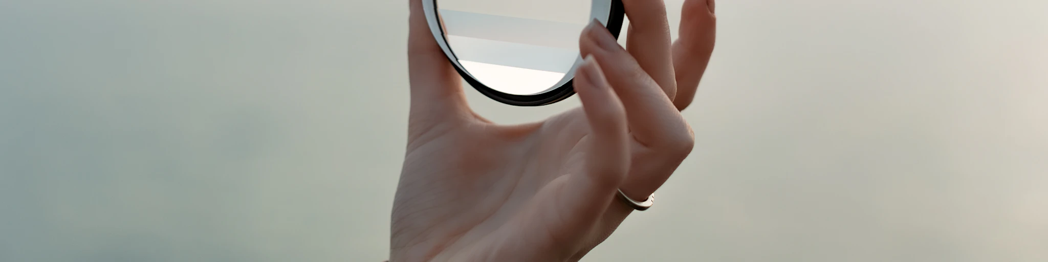 a hand holding a magnifying glass over a body of water