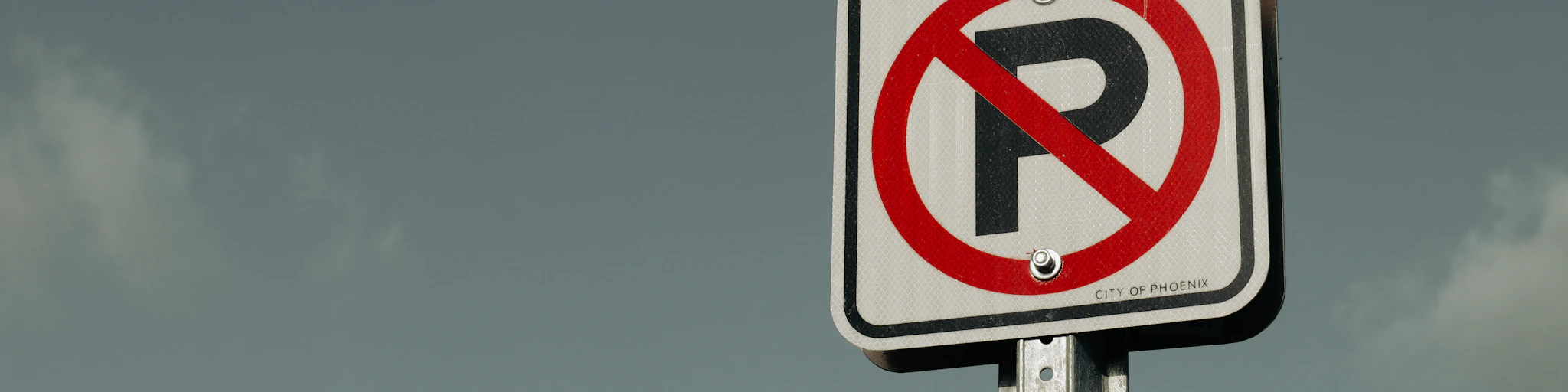 a no parking sign with a sky background