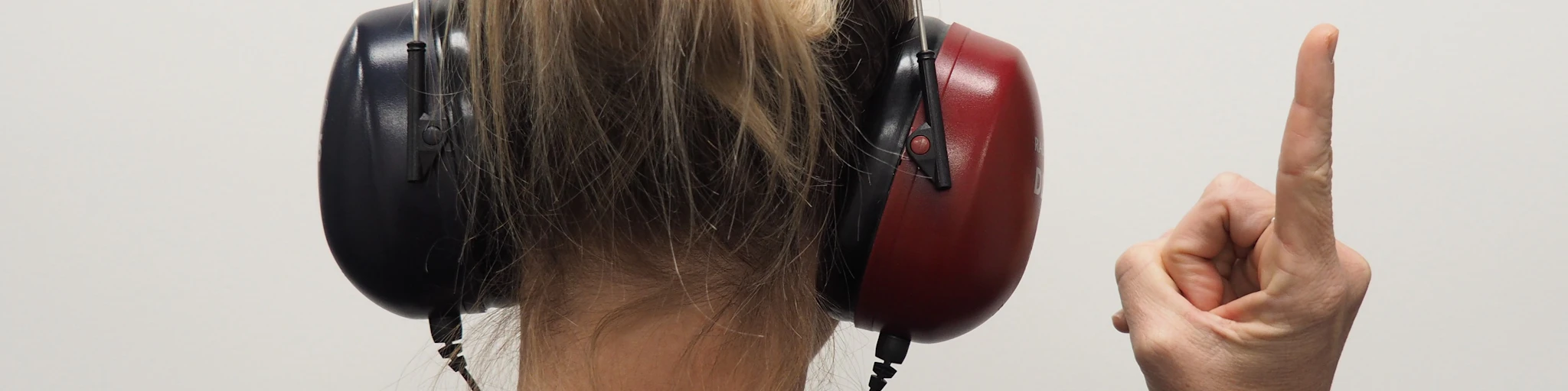 a woman wearing headphones pointing to the side
