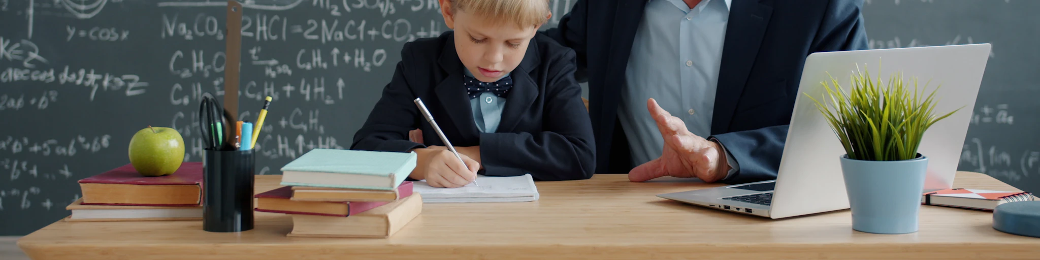 Elderly man teaching young boy math at desk.